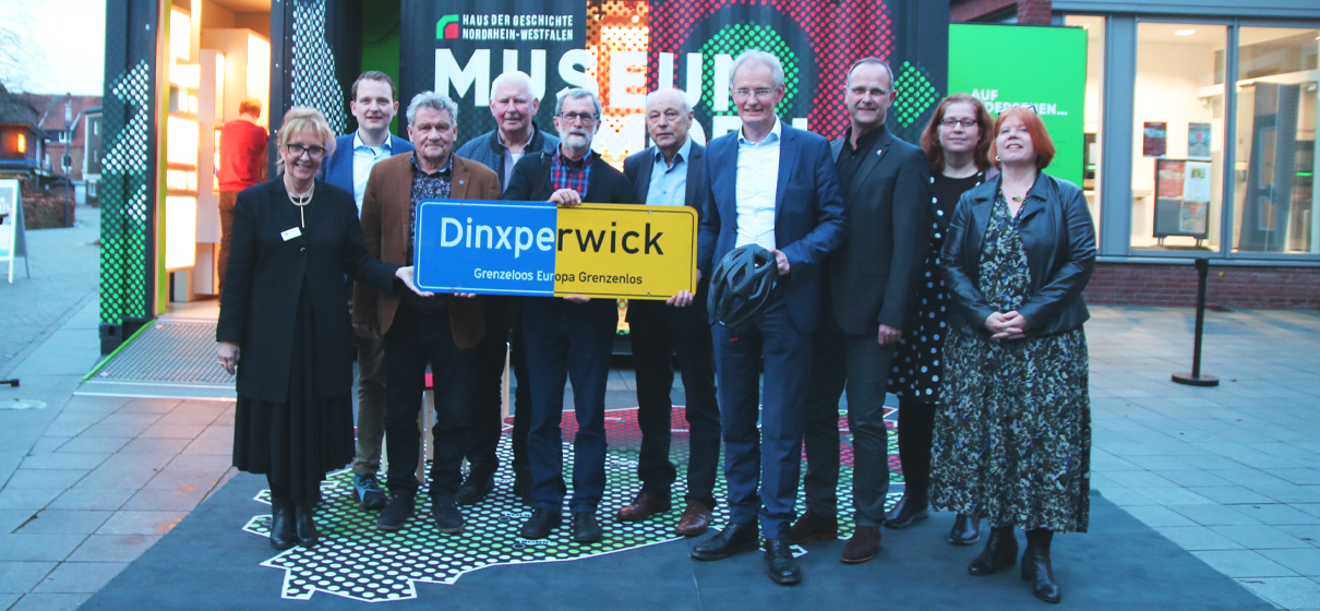 Das Schild „Dinxperwick“ als Symbol für grenzüberschreitende Freundschaft: Übergabe ans „Haus der Geschichte NRW“ mit Dr. Gabriele Uelsberg (links), den Vertretern „Dinxperwicks“ Freek Diersen, Werner Brand, Bertie Bussink und Johannes Hoven (hinter dem Schild) und daneben Kreisdirektor Dr. Ansgar Hörster sowie weitere Beteiligte (Foto Kreis Borken – Der Landrat)